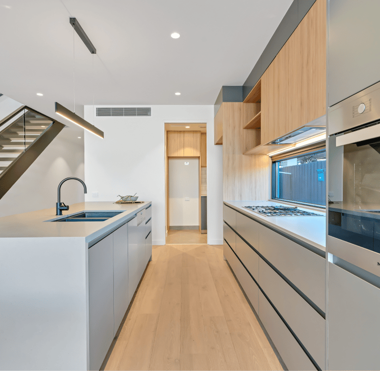 Modern kitchen with sleek cabinetry, built-in appliances, and under-stair sink area