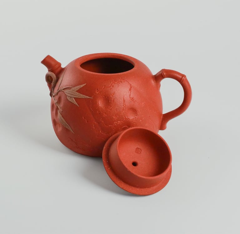 an teapot and its lid against a gray-white background.