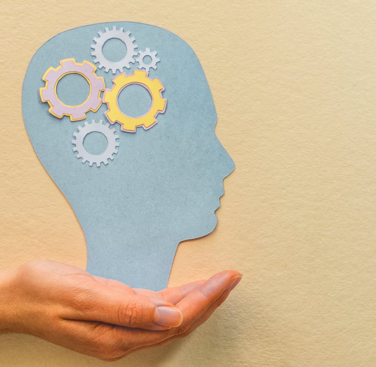 Nell'immagine si vede una mano che sostiene la sagoma di una testa, con degli ingranaggi lavoranti