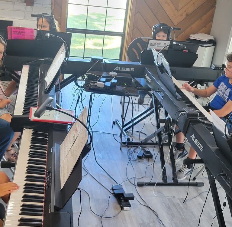 a group of kids sitting at pianos with a teacher