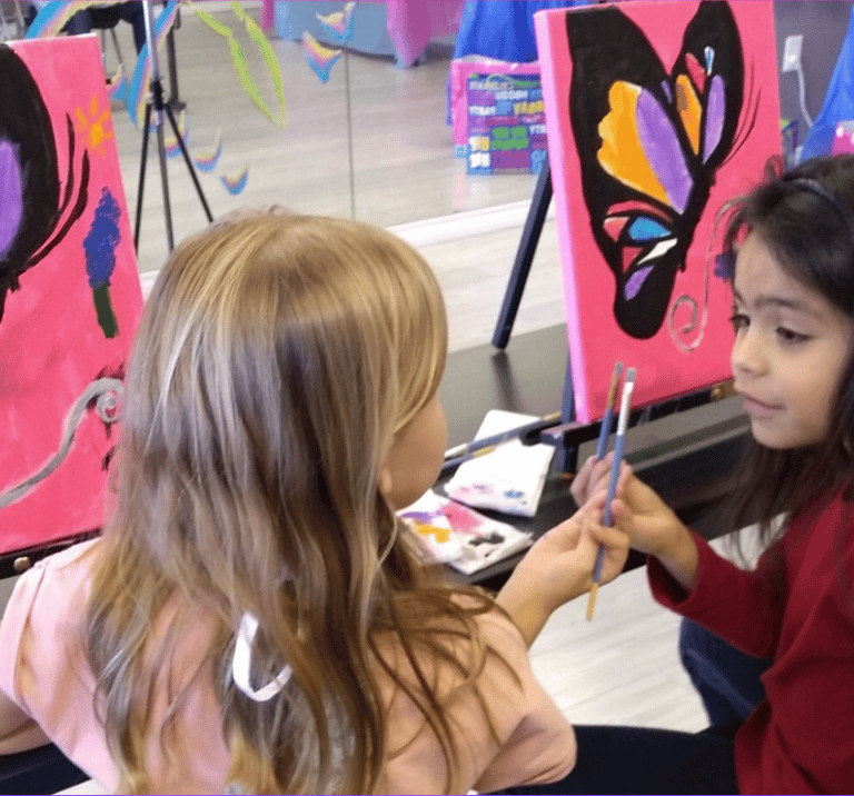 two little girls painting a butterfly on a canvas