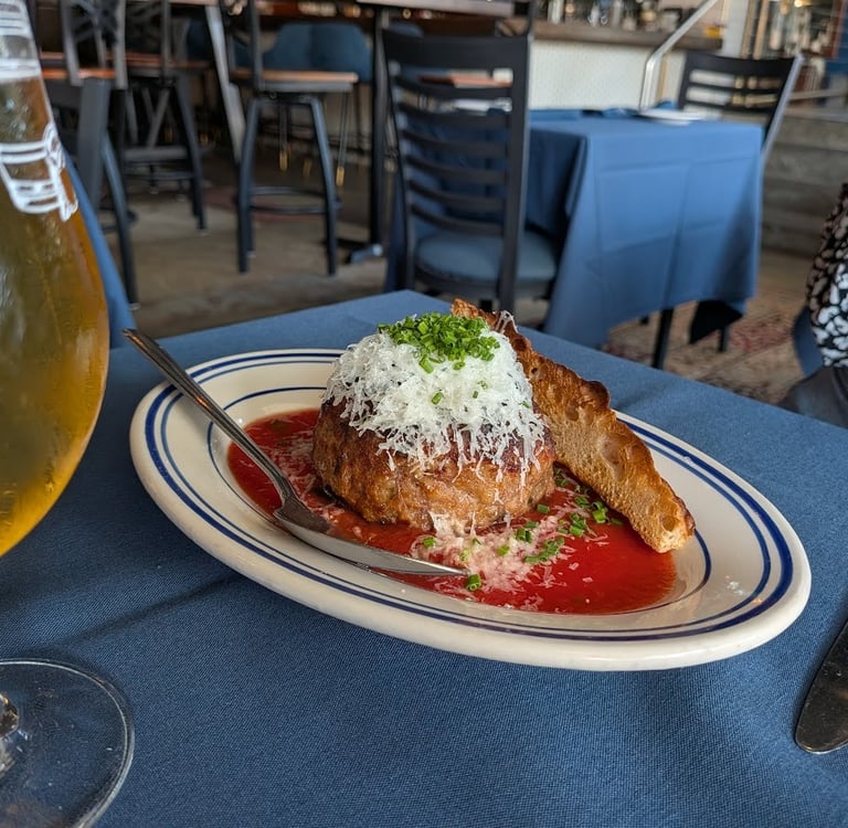 oversized meatball on a plate with sauce