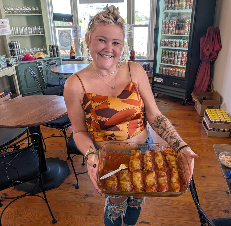 Smiling woman holding a tray of food surrounded by tables and chairs