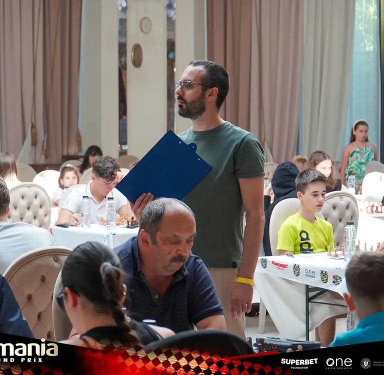 FIDE Arbiter Vlad Ghita holding a clipboard in the middle of a tournament hall and watching games