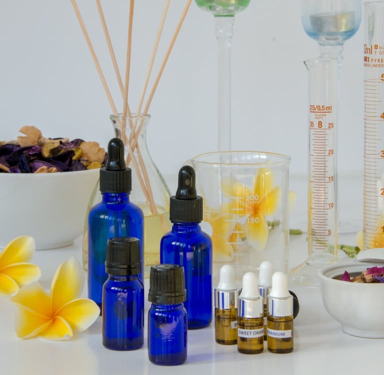 Blue glass apothecary bottles with essential oils, frangipani flowers, and laboratory glassware for aromatherapy.
