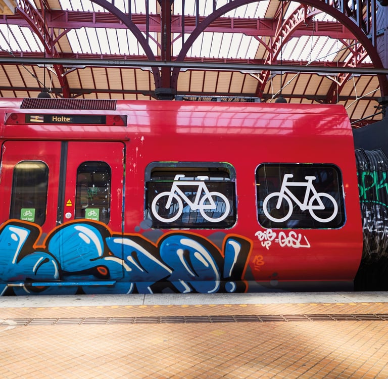 red train with symbols of bicylces at a train station with grafitti on it