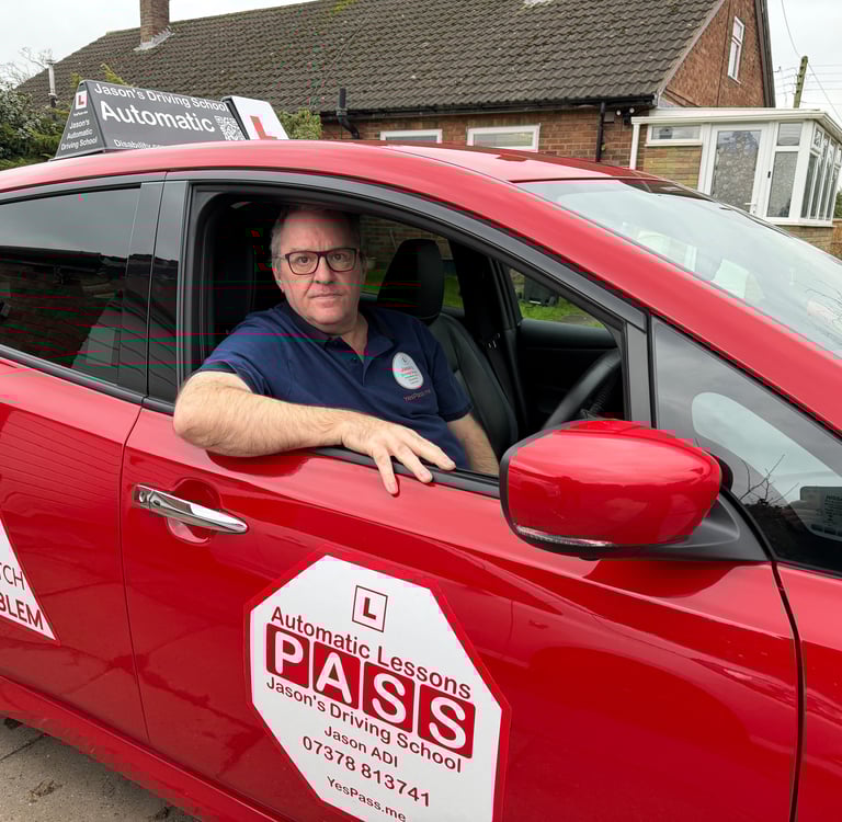 Professional driving instructor in a red automatic driving school car offering lessons for learner drivers.