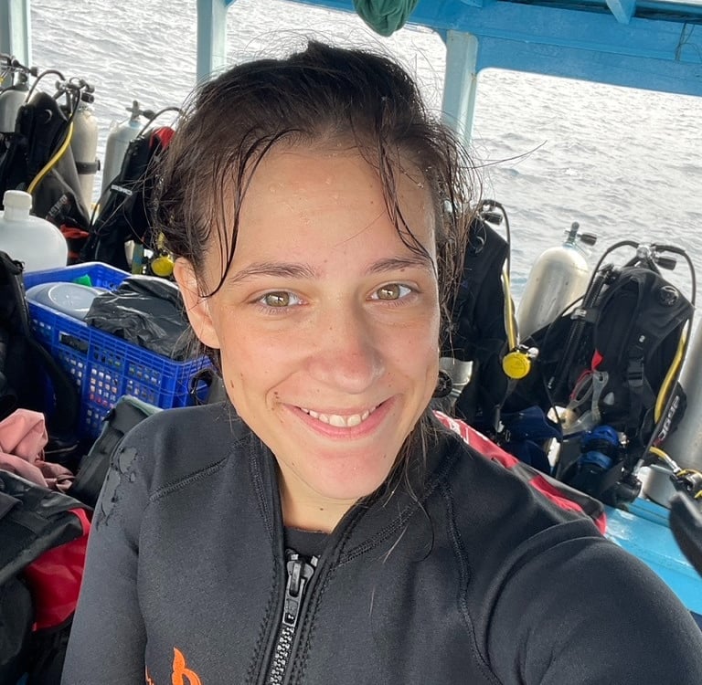 a woman in a wetsuit is smiling and was scuba diving