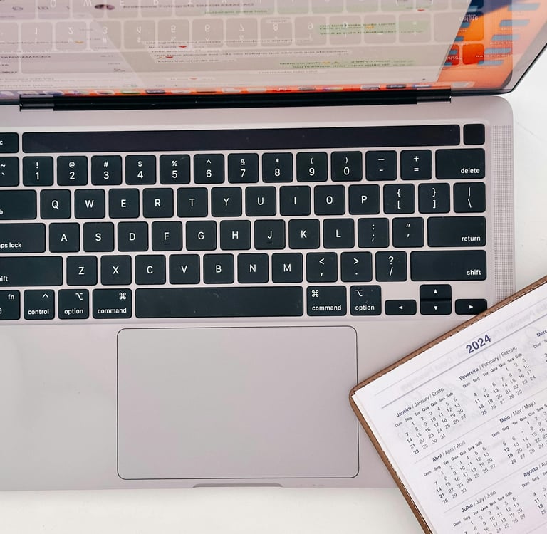An open calendar planner, slightly laid over the keyboard of an open laptop.