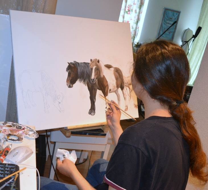 a woman is painting two ponies on a easel