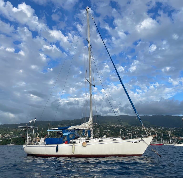 Sailboat Tauha behind the reef in crystal-clear waters near Tahiti, French Polynesia