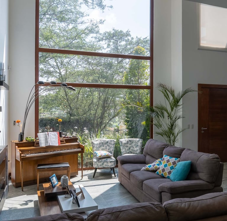 fotografía inmobiliaria quito ecuador tumbaco gran sala de estar con muebles, piano y un gran ventanal con luz natural