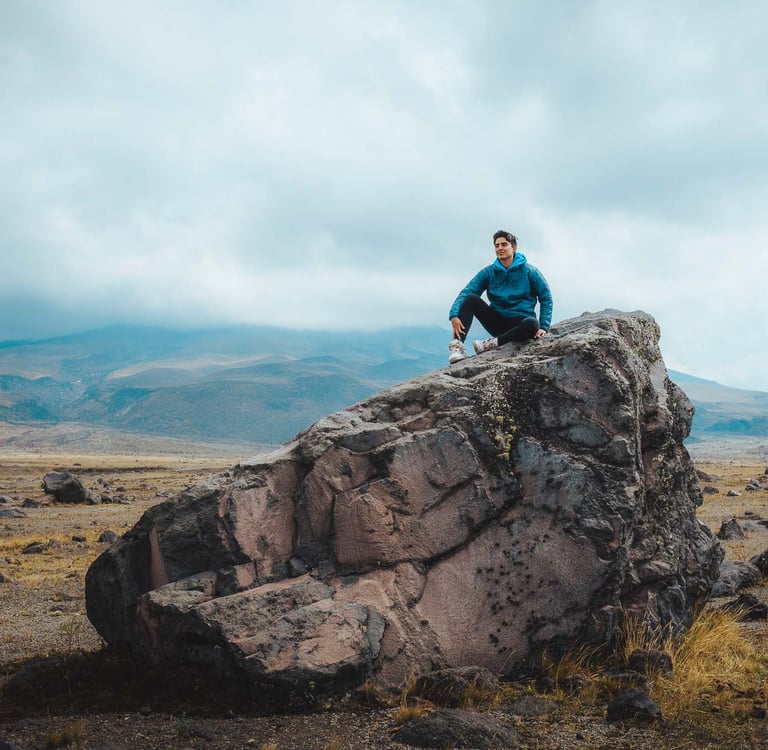 Fotografía de retrato profesional de aventura de un joven sentado en la cima de una roca en un paisaje hermoso de montaña