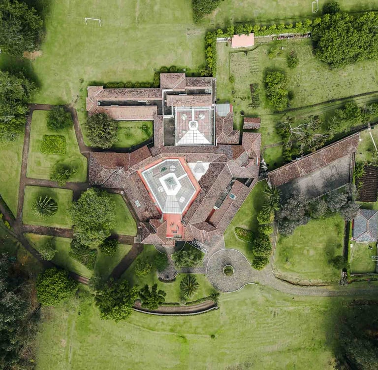 Fotografía con dron de mansión colonial de paredes blancas con techo naranja, cúpulas rodeada de naturaleza Quito Ecuador