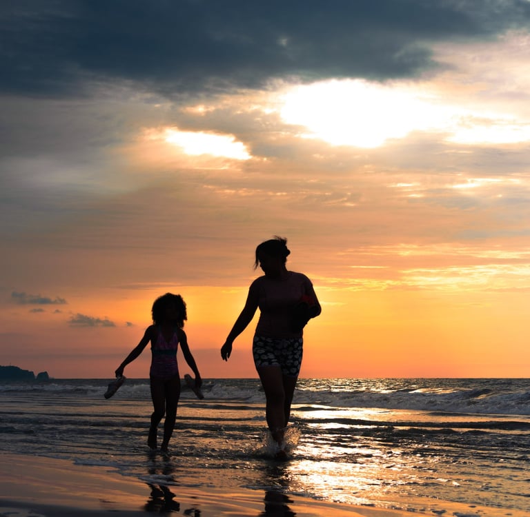 Retrato de una madre y su hija caminando por el agua de la playa en un atardecer