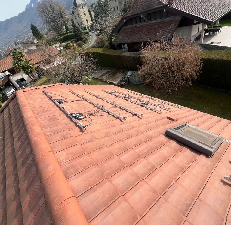 installation des rails et préparation du câblage pour panneaux solaires sur toiture pentue face au lac Léman