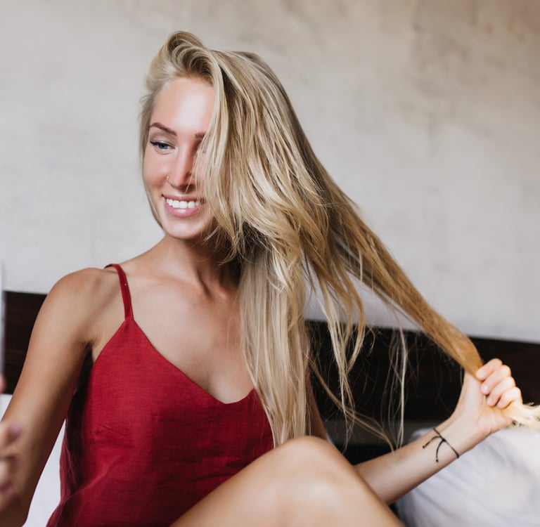 Smiling female content creator taking a selfie at home while holding her long hair