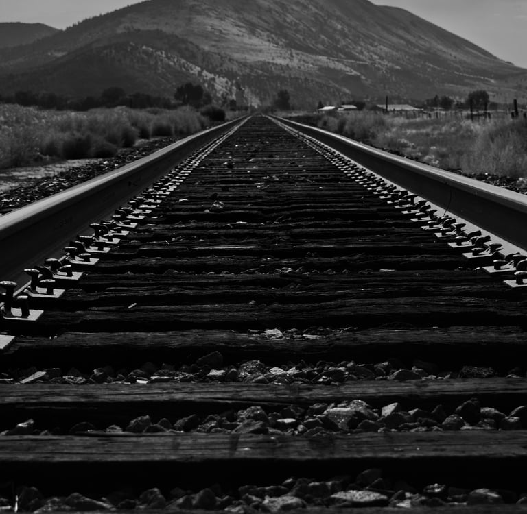 a train track with a mountain in the background taken by Jordan Boyle of JJ Everitt Photography