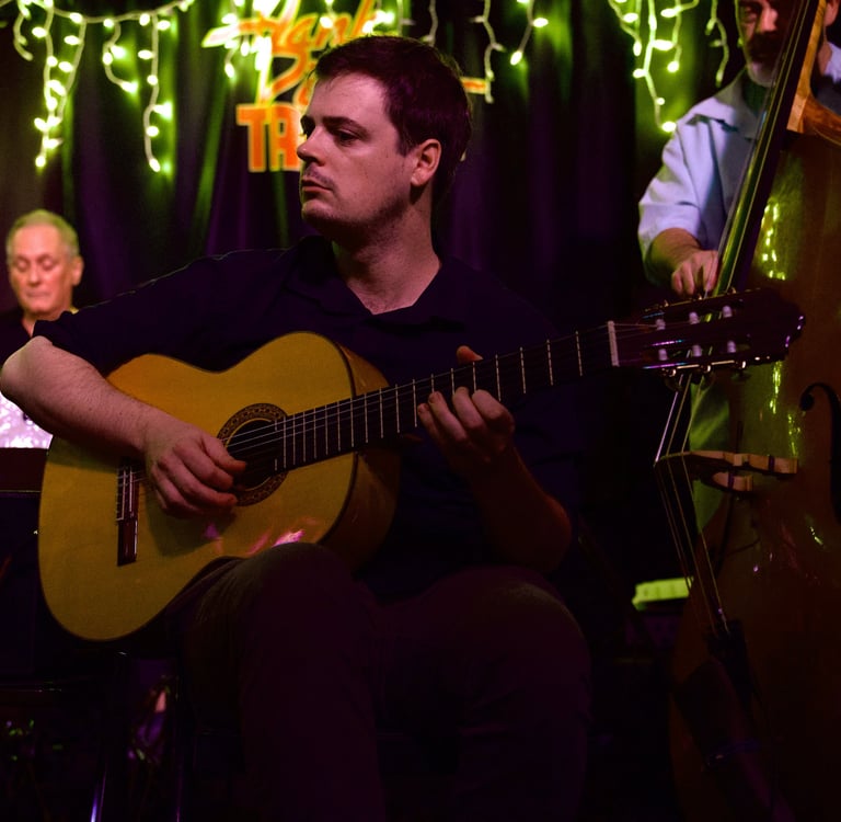 a man (rob coleman) playing acoustic guitar with a drummer and bassist
