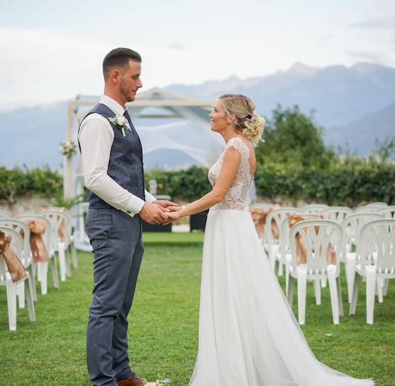 Photo d'un couple de mariés face à face se tenant la main sur le lieux de leur cérémonie de mariage
