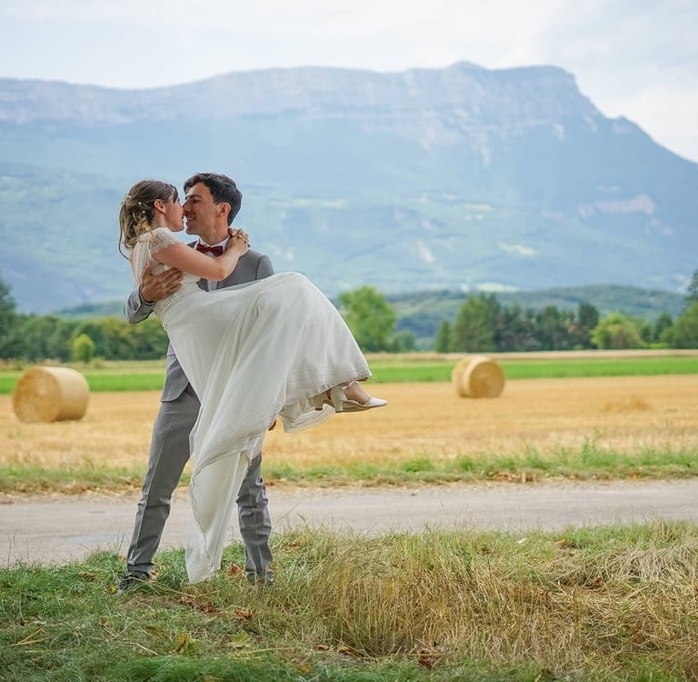 Photo de mariage, le marié porte la mariée dans ses bras dans un champ