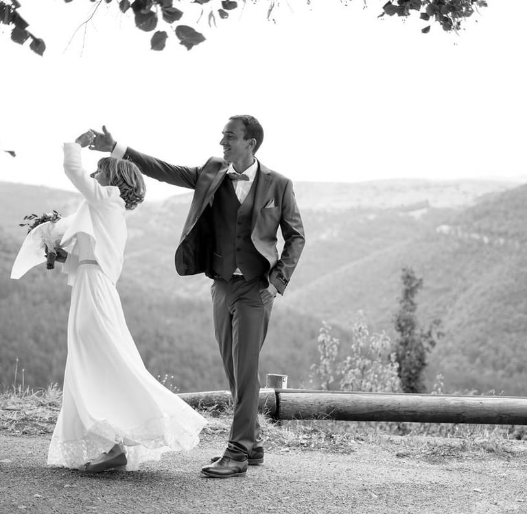 Photo en noir et blanc de mariés qui dansent devant la mairie lors de leur journée de mariage 