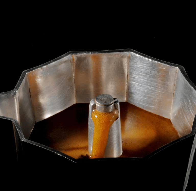 "Cafeteira italiana com a tampa aberta cheia de café fresco, ilustrando o preparo de café  Curitiba