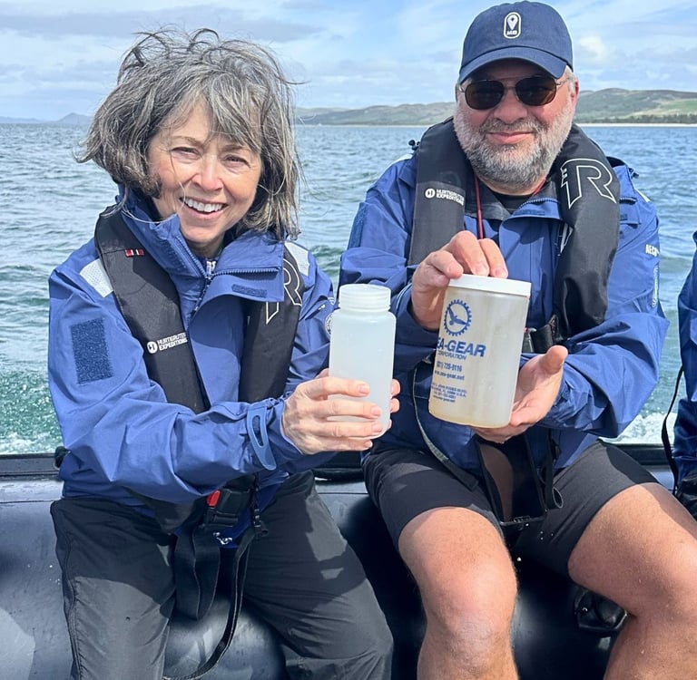 Two researchers on a boat collect ocean water samples for marine conservation research.