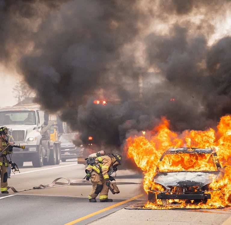 a firefighter standing in front of a car that is on fire