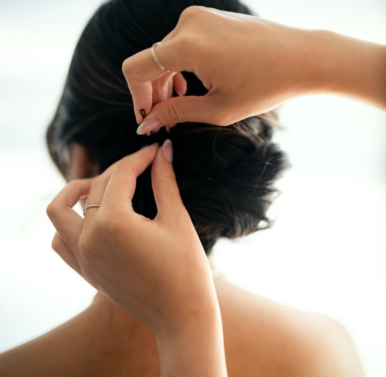 coiffeuse qui ajoute une bobbipin dans les cheveux de la mariée