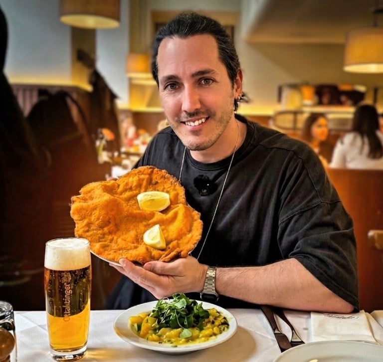 Primer plano de un Schnitzel de Viena gigante servido con rodajas de limón, guarnición de ensalada