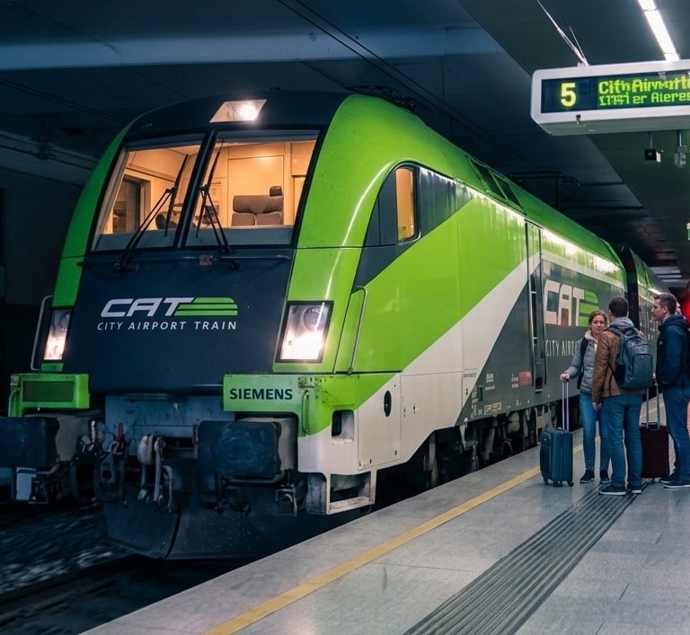 Un tren verde lima del City Airport Train está en el andén de una estación subterránea moderna.