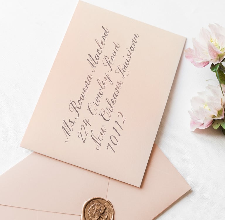 light pink envelope with an address written in calligraphy script in brown ink