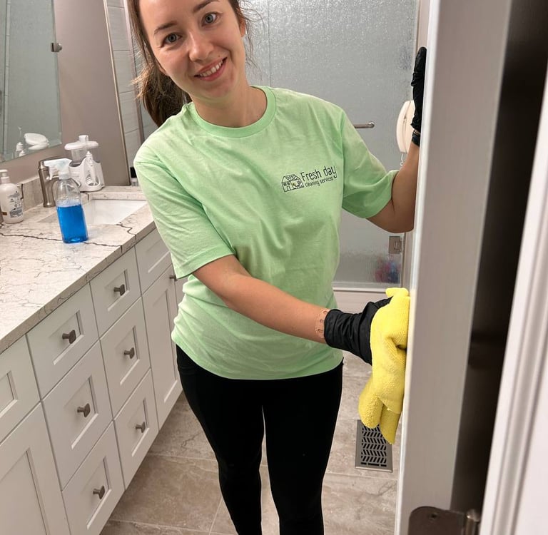 a woman in a green shirt is cleaning a bathroom