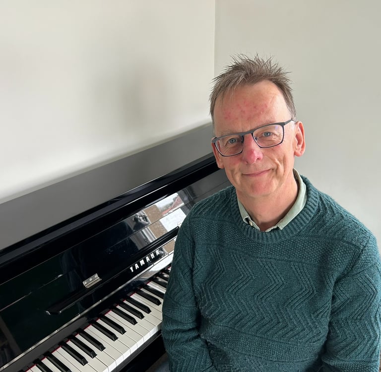 Photo of Steven with a piano behind him