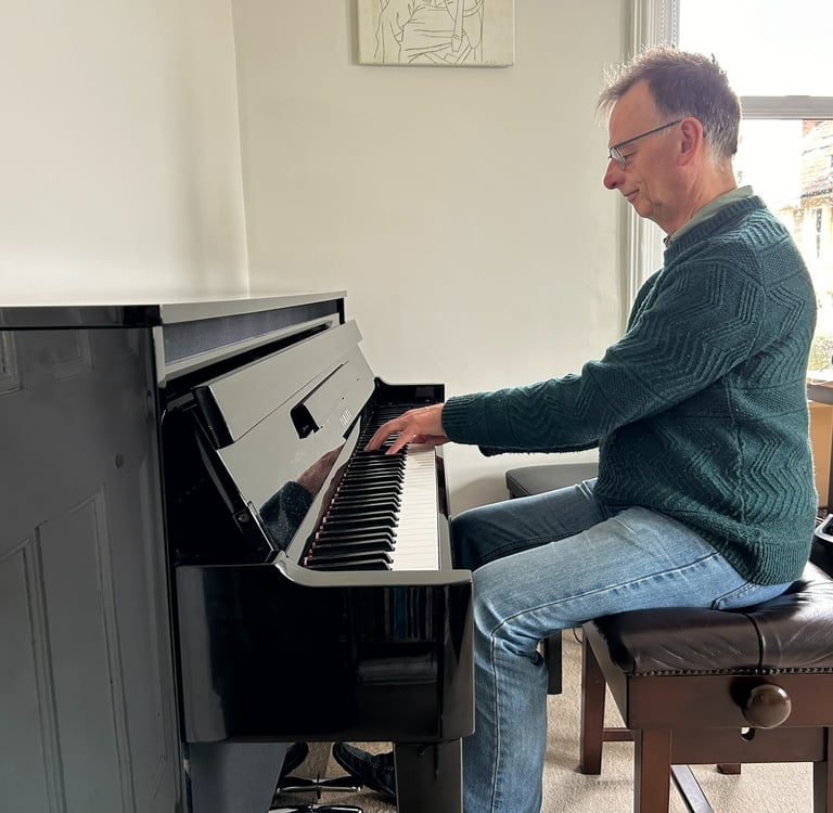 Photo of Steven playing an upright piano