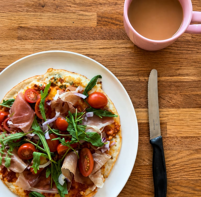 High protein breakfast egg pancake with prosciutto, cherry tomatoes, arugula and melted cheese serve