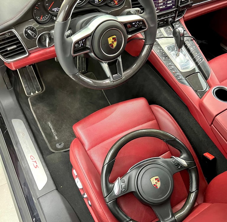 Luxury Porsche GTS interior featuring red leather seats and a carbon fiber steering wheel.