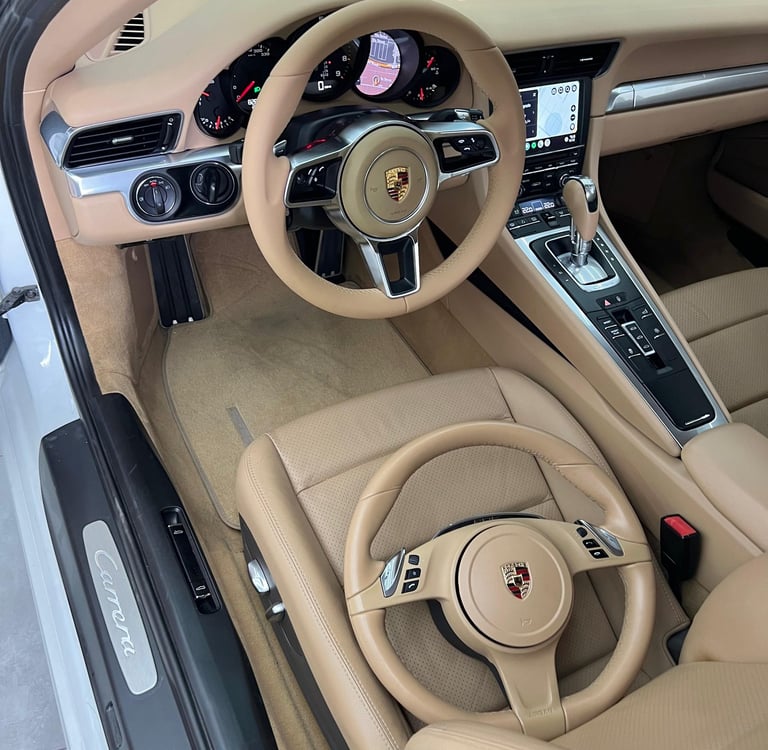 Luxurious tan leather Porsche Carrera interior featuring two matching steering wheels and dashboard.