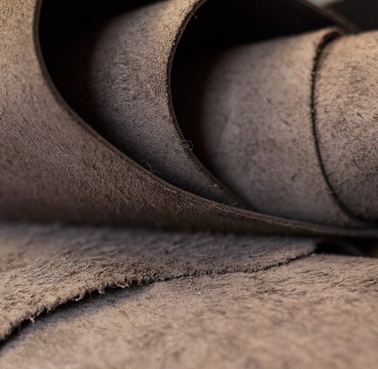 Close-up of high-quality brown suede leather fabric roll with a soft, napped texture for upholstery or crafts.