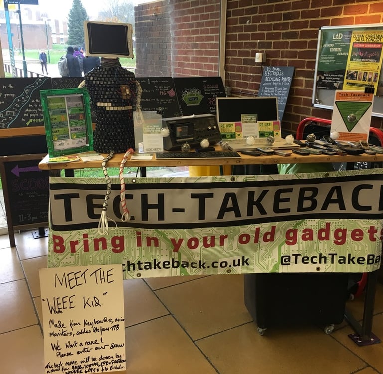 Tech-Takeback's first event. Old tech sits on a table with a homemade Tech-Takeback banner.