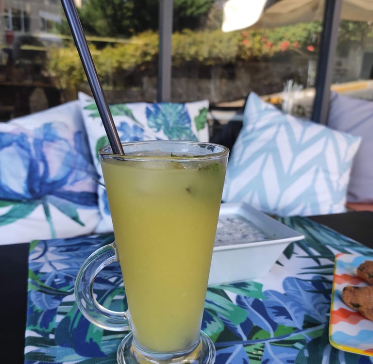 A refreshing glass of homemade lemonade with condensation droplets, set against the cafe’s soft pastel exterior.