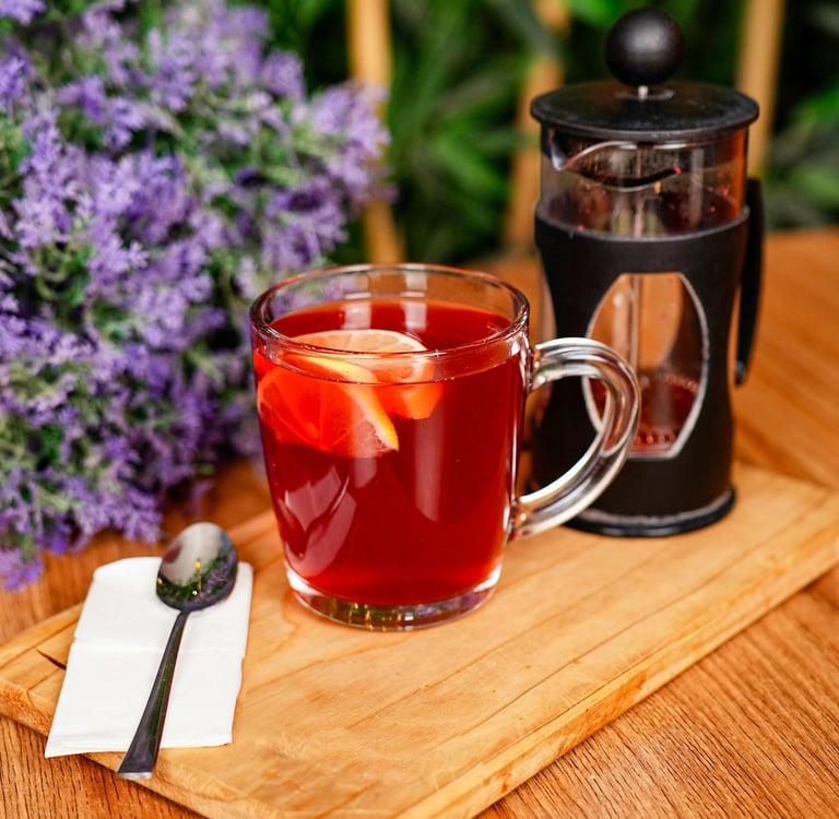 üzerinde french press ve bir fincan bitki çayı bulunan tahta servis tepsisi