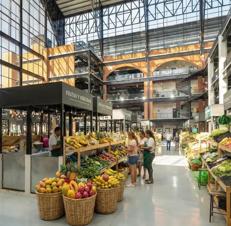 Customers shopping for fresh tropical fruit at a modern indoor market with glass ceilings.