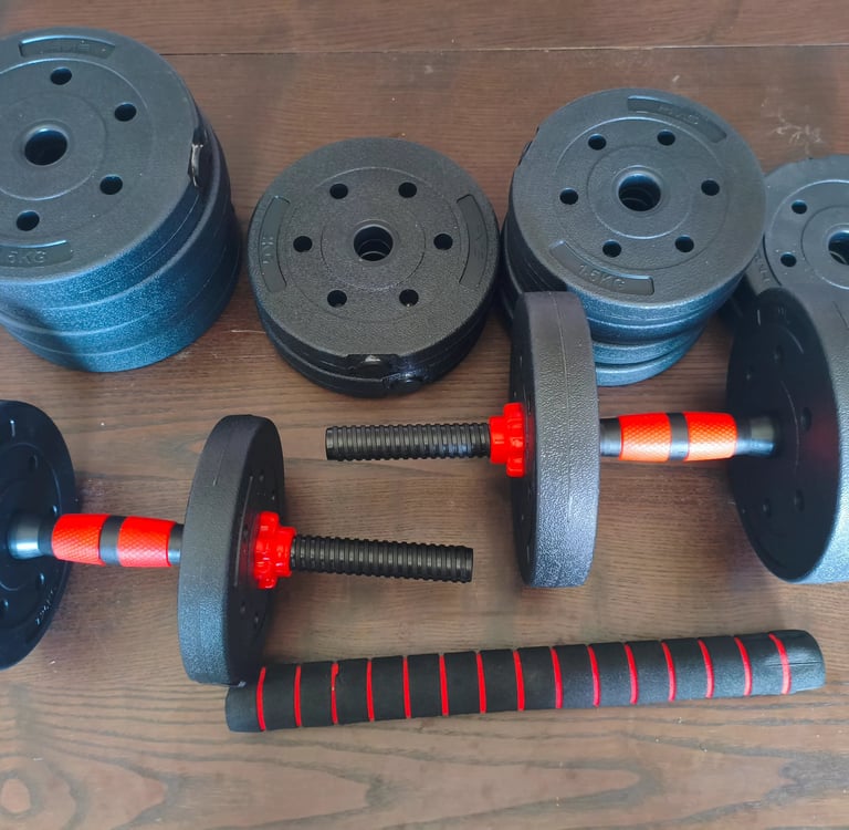 Kit de halteres ajustáveis JUPPLIES com discos pretos e punhos com detalhes vermelhos numa bancada d
