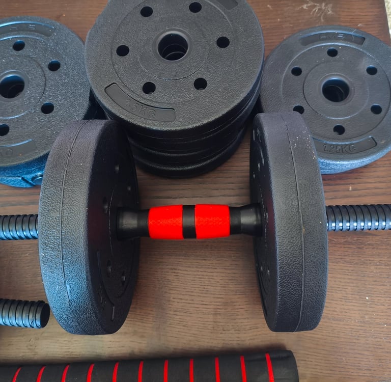 Detalhe do punho vermelho e preto dos halteres ajustáveis JUPPLIES com discos de peso empilhados