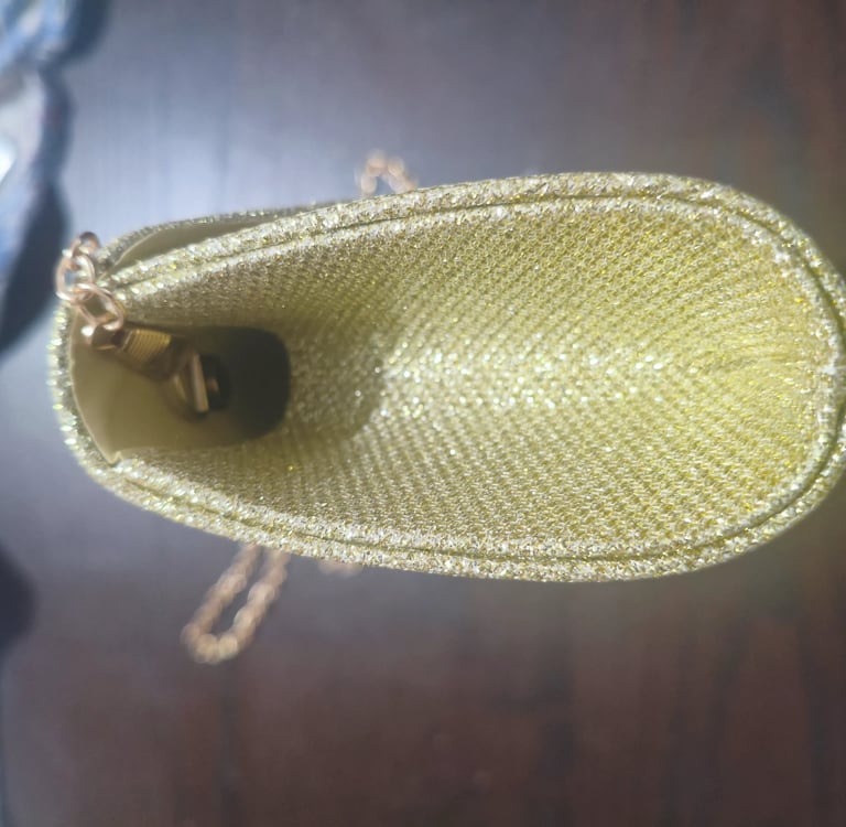 Teste de abertura lateral de mala clutch dourada de festa para avaliar a capacidade e flexibilidade.