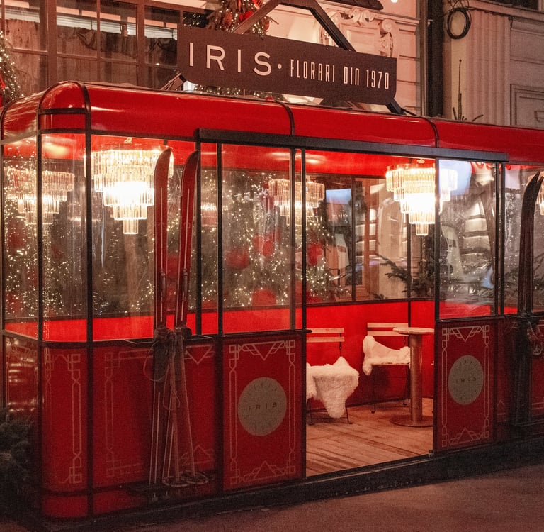 A red vintage ski gondola decorated for Christmas with chandeliers and cozy seating inside.