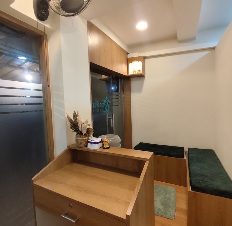 A modern dental clinic reception area featuring a wooden desk and velvet waiting room benches.