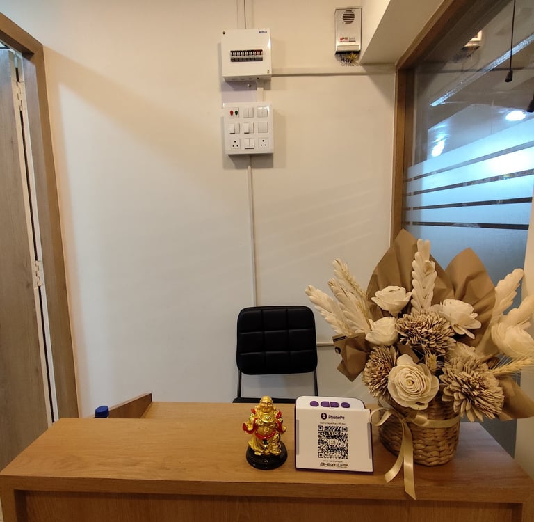 dental clinic reception desk with flower arrangement, golden Buddha statue, and PhonePe QR scanner.